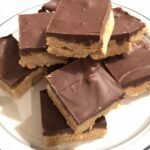 A plate of Easy No Bake Peanut Butter Bars with a smooth chocolate topping.