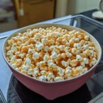 A bowl of Gooey Marshmallow Caramel Popcorn with melted marshmallows and caramel drizzle