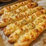 Freshly baked Homemade Cheesy Garlic Breadsticks with melted cheese and garlic butter, served on a wooden board.