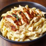 A bowl of White Cheddar Chicken Pasta garnished with fresh parsley.