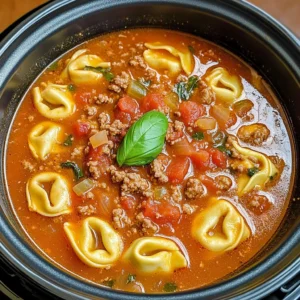 A bowl of Slow Cooker Tomato Tortellini Soup with Ground Beef garnished with fresh basil and Parmesan cheese