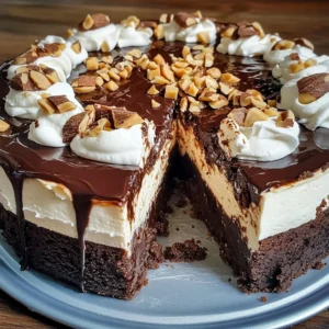 A rich and creamy Hot Fudge Sundae Brownie Cheesecake topped with ganache and whipped cream.v