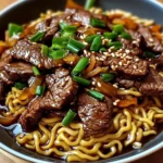 A bowl of Steak Stir-Fried Ramen with green onions and sesame seeds