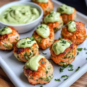 Baked salmon meatballs drizzled with creamy avocado sauce on a white plate