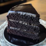 A slice of Black Velvet Cake with cream cheese frosting, served on a plate