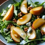 A plate of caramelized pear and blue cheese salad with toasted walnuts and balsamic glaze.