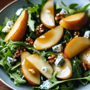 A plate of caramelized pear and blue cheese salad with toasted walnuts and balsamic glaze.