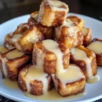 A plate of Cinnamon Roll French Toast Bites drizzled with icing