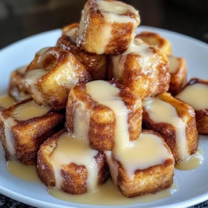 A plate of Cinnamon Roll French Toast Bites drizzled with icing