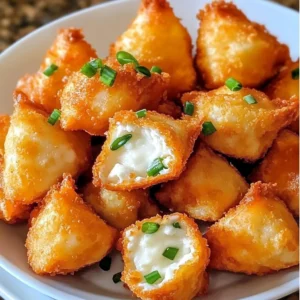 A plate of golden-brown Crab Rangoon Bombs served with dipping sauce.