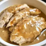 Plate of crockpot chicken and gravy over mashed potatoes with parsley garnish