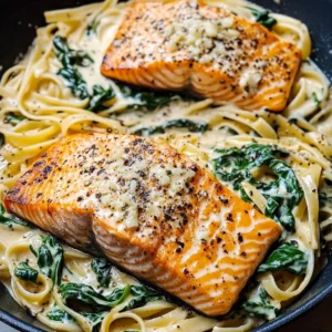 A plate of creamy spinach linguine topped with a seared garlic butter salmon fillet