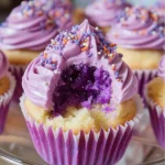 A batch of Grape Crush Cupcakes with a vibrant purple hue, topped with frosting and grape sprinkles.