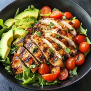 A bowl of Grilled Chicken Avocado Salad with cherry tomatoes, lettuce, and a drizzle of lime dressing.