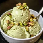 A scoop of High Protein Pistachio Ice Cream garnished with crushed pistachios.