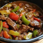 A bowl of Pepper Steak in a Crock Pot served over rice, garnished with fresh herbs