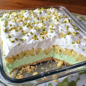 A slice of Pineapple Paradise Cake topped with chopped pistachios and whipped cream.