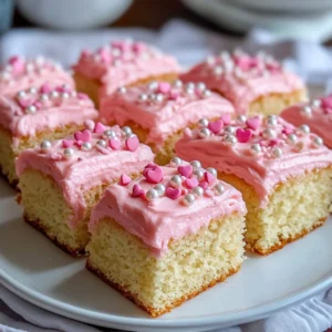 A plate of Pink Vanilla Cake Squares with pink buttercream frosting and sprinkles.