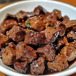 Crockpot Steak Bites served in a bowl with sauce and parsley garnish