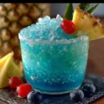 Colorful Frozen Smurf Punch in a glass with ice and fruit garnishes