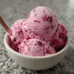 Homemade mulberry ice cream topped with rosewater in a vibrant bowl