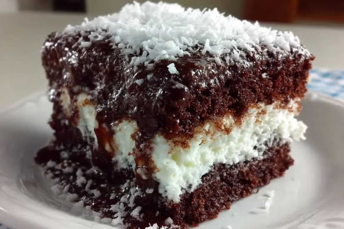 Delicious slice of Mounds cake topped with chocolate and coconut flakes