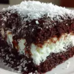 Delicious slice of Mounds cake topped with chocolate and coconut flakes