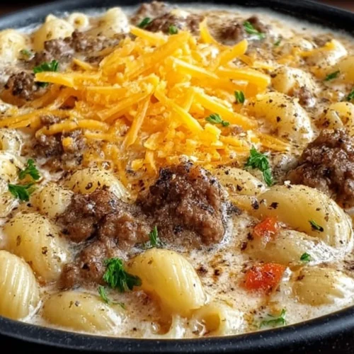 Bowl of cheeseburger macaroni soup topped with cheese and herbs