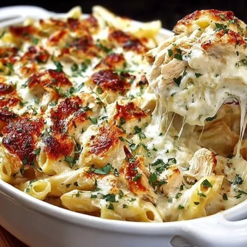 Delicious Chicken Alfredo Baked Ziti topped with cheese and herbs.