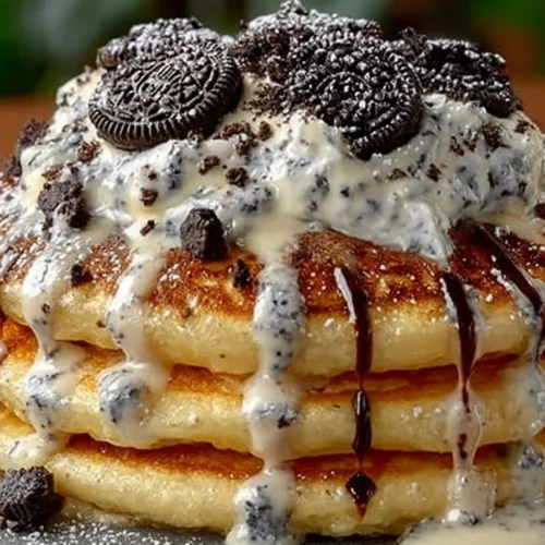 Oreo pancakes topped with cream cheese drizzle on a plate