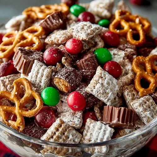 A bowl of Reindeer Chow with colorful ingredients and festive decorations.