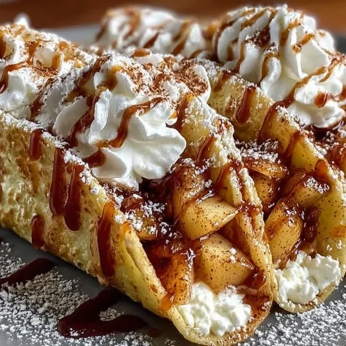 Delicious apple pie cheesecake tacos topped with whipped cream and caramel sauce.