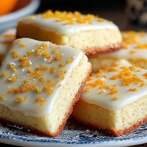 Cardamom shortbread cookies topped with a sweet orange glaze on a plate.