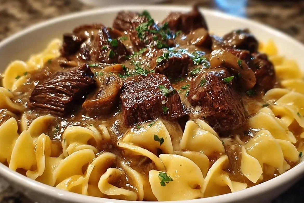 Crockpot beef tips and noodles dish with vegetables and herbs.