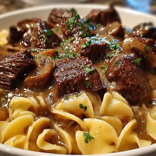Crockpot beef tips and noodles dish with vegetables and herbs.
