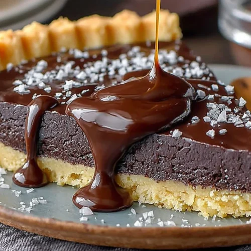 Decadent dark chocolate tart garnished with fresh berries and mint leaves